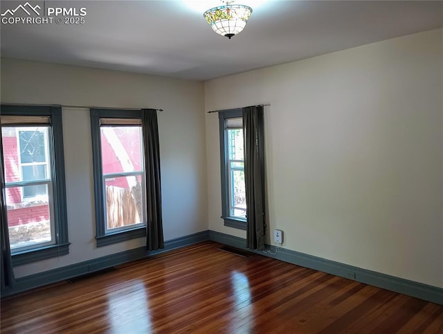 unfurnished room with visible vents, baseboards, and wood finished floors