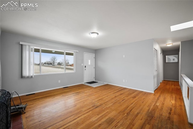 entryway featuring a skylight, wood finished floors, and baseboards