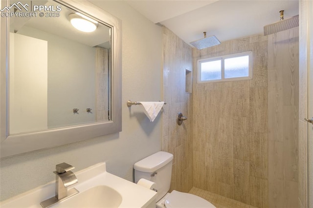 full bath featuring toilet, a tile shower, and vanity