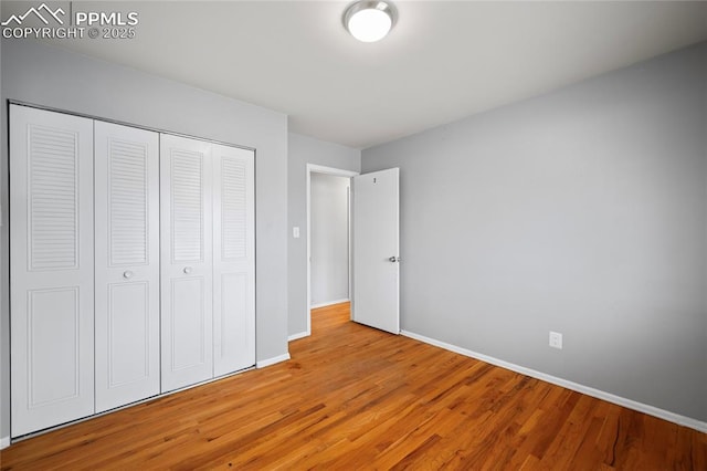 unfurnished bedroom featuring a closet, baseboards, and wood finished floors