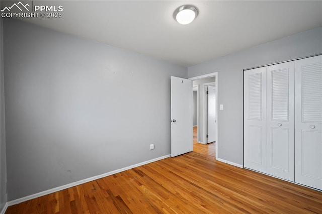 unfurnished bedroom featuring a closet, baseboards, and wood finished floors