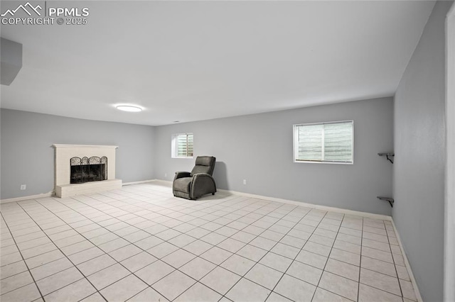 unfurnished room featuring a fireplace with raised hearth and baseboards