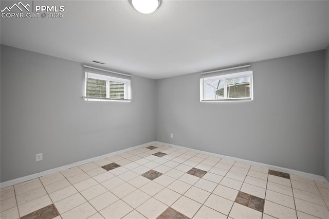 tiled spare room featuring visible vents, plenty of natural light, and baseboards