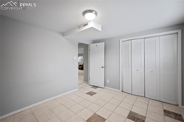 unfurnished bedroom with light tile patterned floors, baseboards, visible vents, and a closet