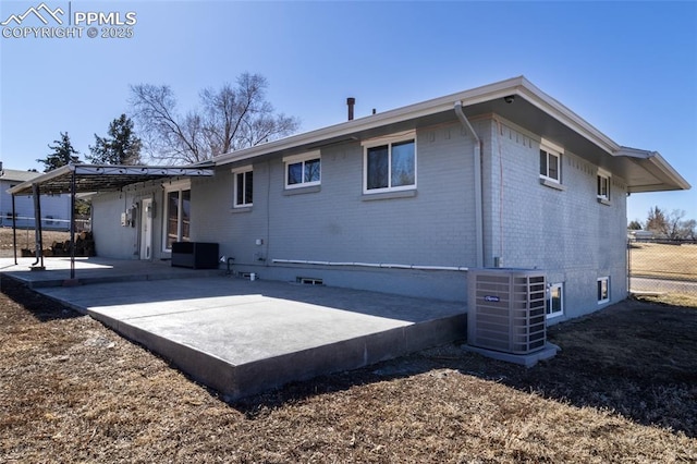 back of house with brick siding, fence, central AC unit, and a patio