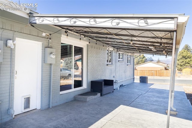 view of patio / terrace with an attached carport, fence, driveway, and central AC unit