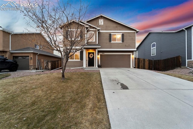 view of front facade with concrete driveway, a yard, an attached garage, and fence