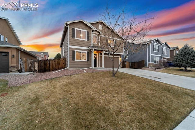 traditional home with a garage, driveway, a front lawn, and fence