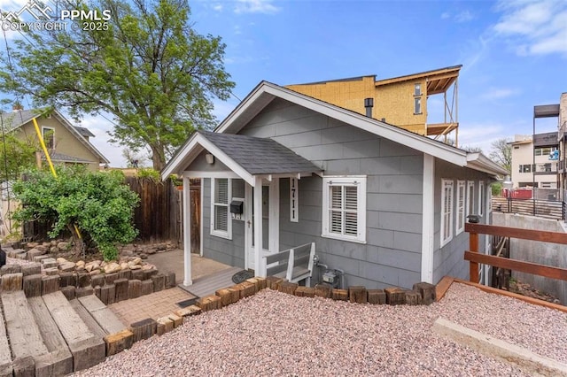 view of front of house with a shingled roof and fence