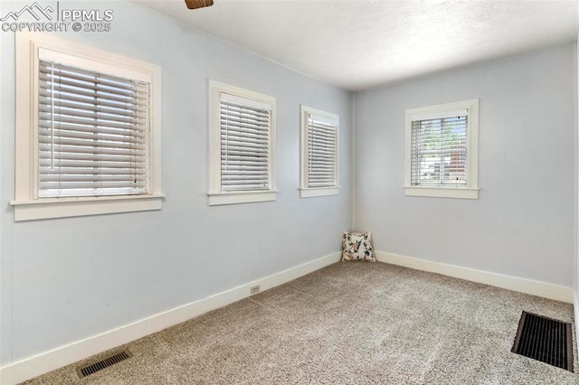 unfurnished room featuring a textured ceiling, carpet, visible vents, and baseboards