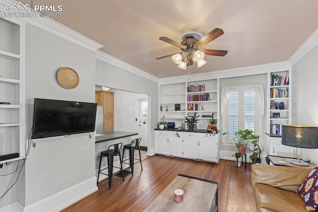 living room with built in shelves, dark wood finished floors, and crown molding