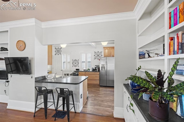 kitchen with stainless steel fridge with ice dispenser, dark countertops, wood finished floors, a peninsula, and crown molding