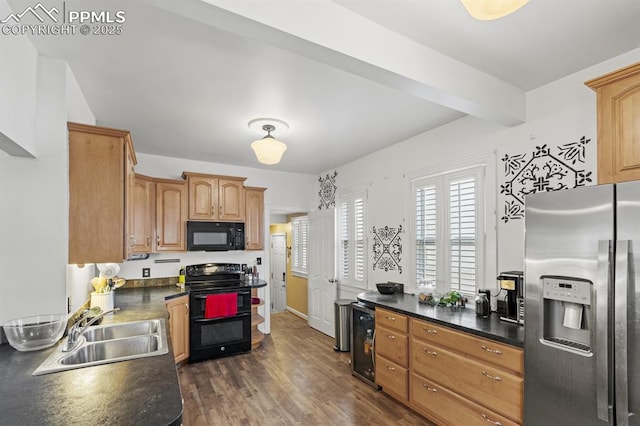 kitchen featuring dark wood-style flooring, dark countertops, a sink, beverage cooler, and black appliances