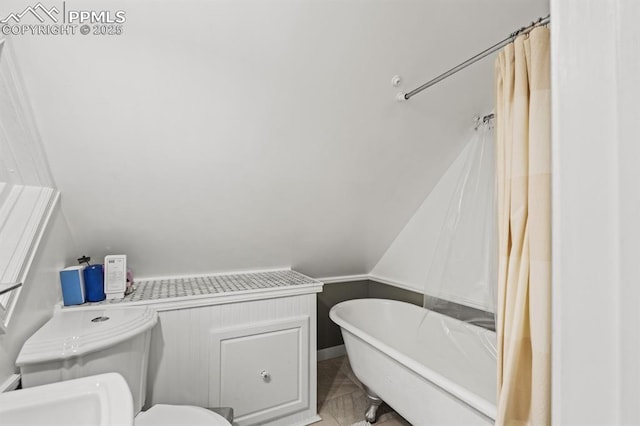 bathroom with lofted ceiling, a freestanding bath, and toilet