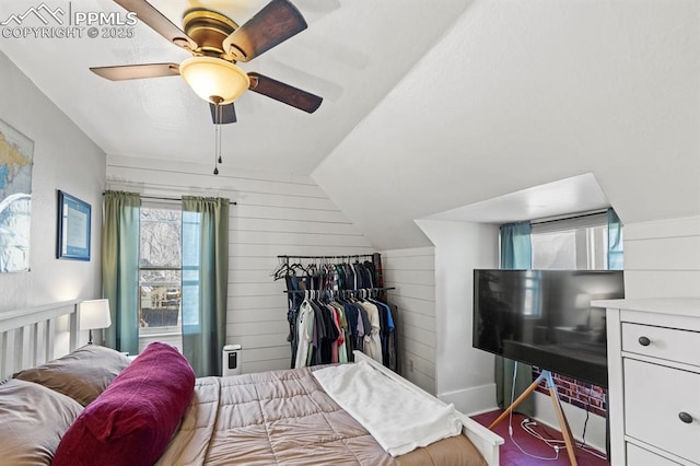 bedroom with a ceiling fan, lofted ceiling, and wood walls