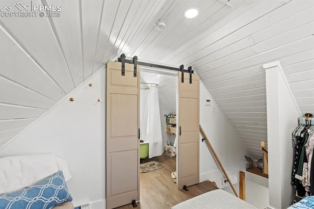 bedroom featuring lofted ceiling, wooden ceiling, light wood-style flooring, and a barn door