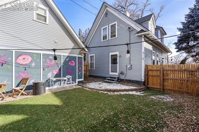 back of property featuring entry steps, fence, and a lawn