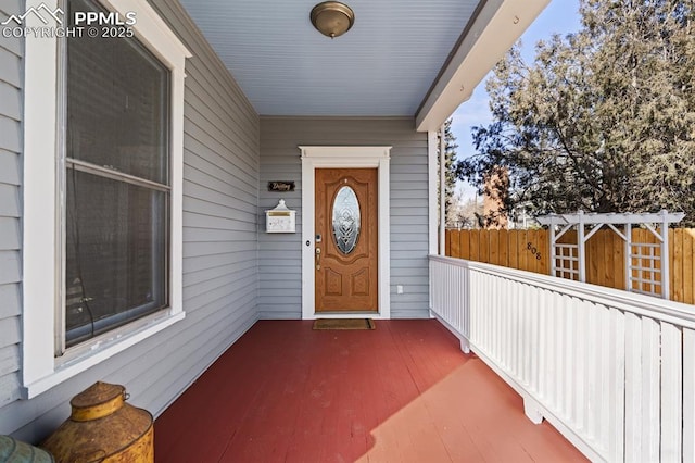 entrance to property with covered porch and fence