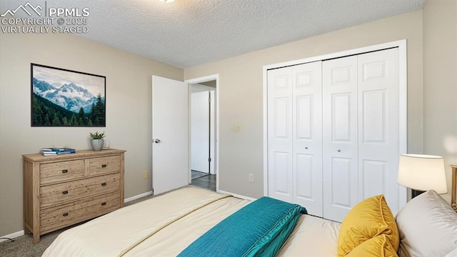 bedroom with a closet, carpet flooring, a textured ceiling, and baseboards