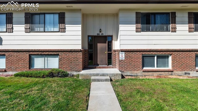 doorway to property featuring a yard and brick siding