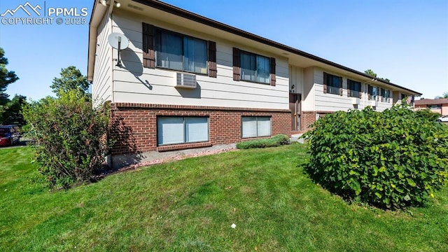 rear view of house featuring a lawn and brick siding