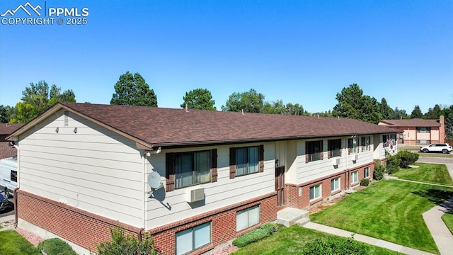 view of front of property featuring brick siding, a shingled roof, and a front lawn