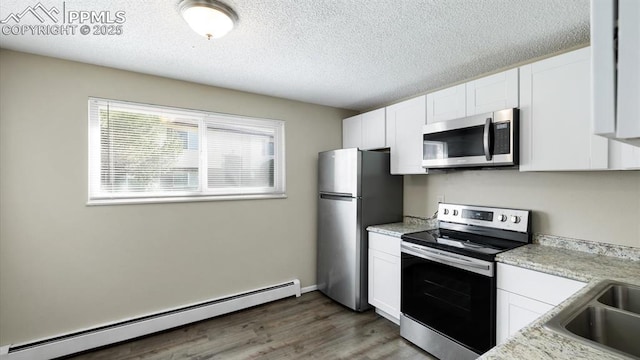 kitchen featuring a textured ceiling, wood finished floors, white cabinetry, appliances with stainless steel finishes, and a baseboard radiator