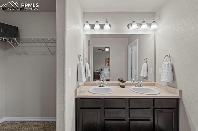 ensuite bathroom with double vanity, a spacious closet, ensuite bath, and a sink