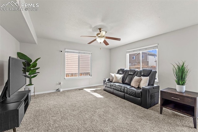 carpeted living room with a textured ceiling, ceiling fan, and baseboards