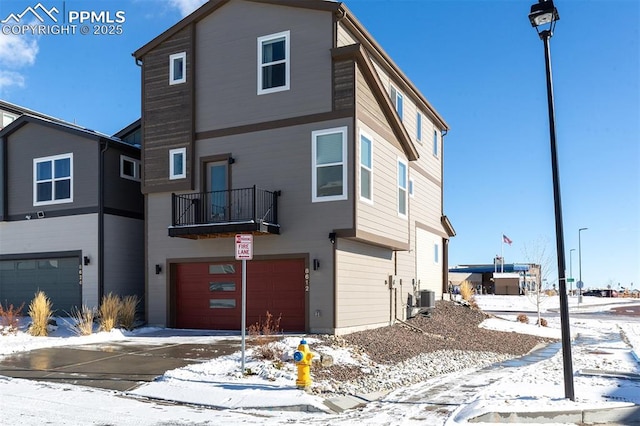 view of front of house with an attached garage, a balcony, and cooling unit