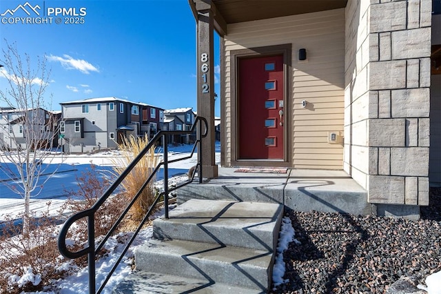 snow covered property entrance featuring a residential view