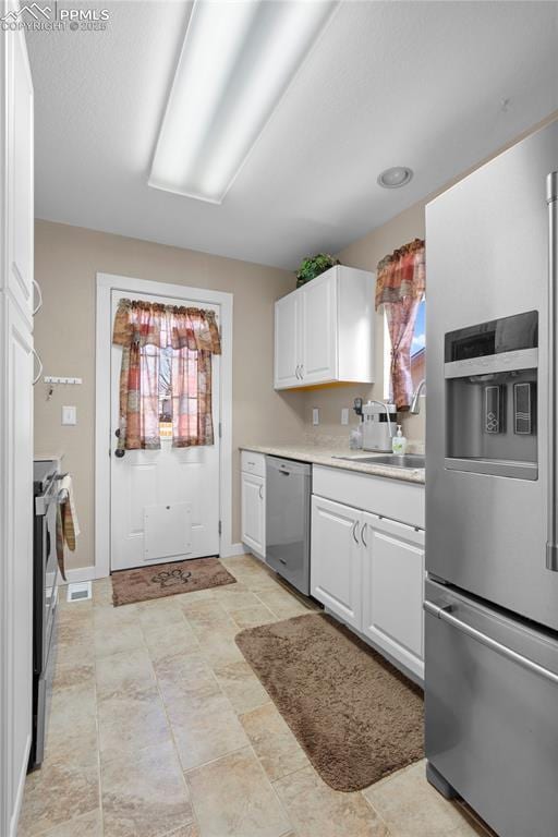 kitchen with appliances with stainless steel finishes, light countertops, white cabinets, and plenty of natural light