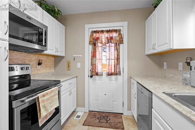 kitchen with visible vents, baseboards, white cabinets, appliances with stainless steel finishes, and backsplash