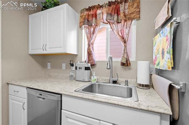 kitchen featuring light countertops, stainless steel dishwasher, a sink, and white cabinetry