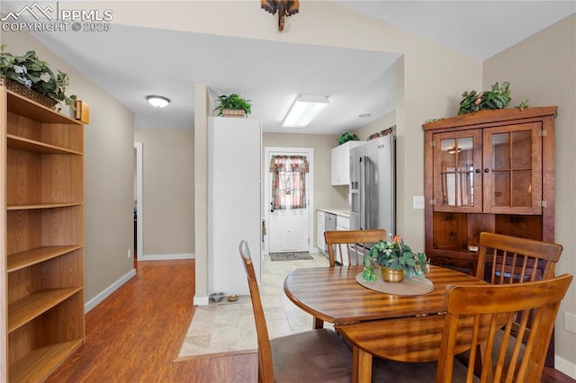 dining area with light wood-type flooring and baseboards