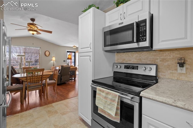 kitchen with white cabinets, vaulted ceiling, and stainless steel appliances