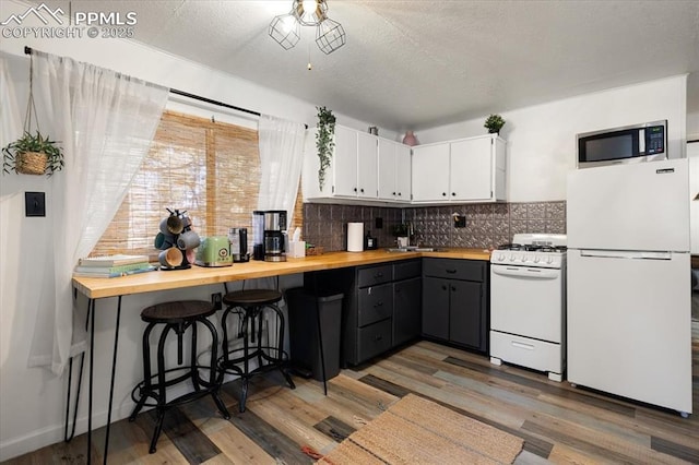 kitchen featuring white appliances, wood counters, decorative backsplash, and a sink