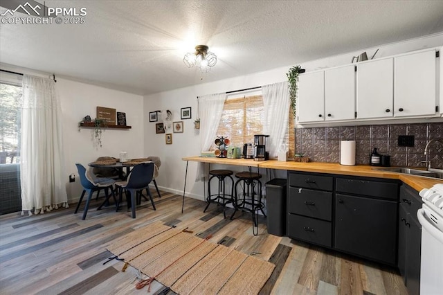 kitchen featuring light wood-type flooring, white cabinetry, a sink, and stove