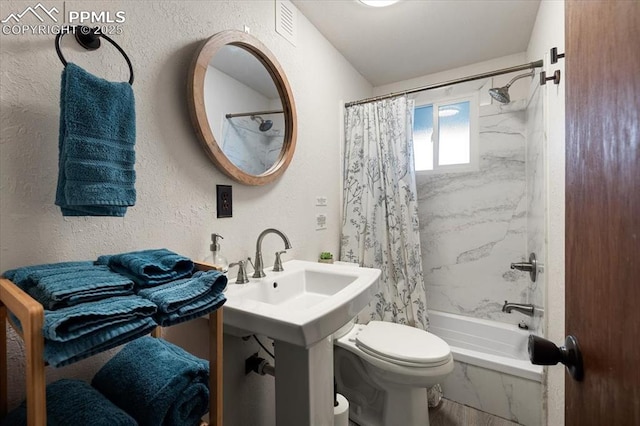 full bathroom with visible vents, a textured wall, shower / bath combo, and toilet