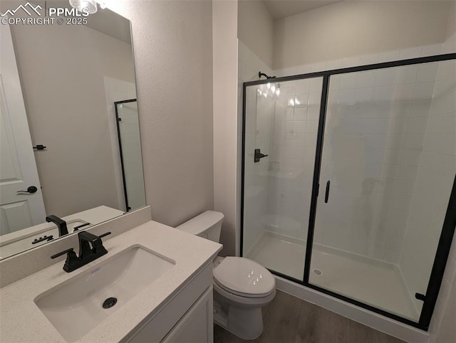 full bathroom with vanity, wood finished floors, a shower stall, and toilet