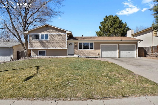 split level home featuring an attached garage, driveway, fence, and a front yard