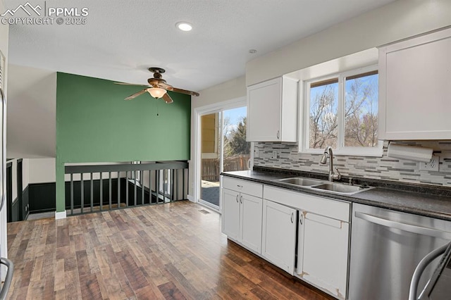 kitchen with a sink, dark countertops, backsplash, and stainless steel dishwasher