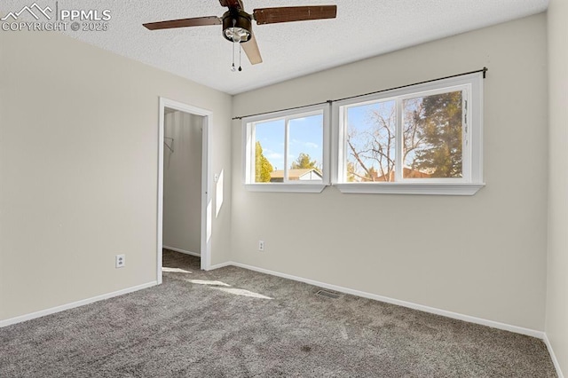 unfurnished bedroom with a spacious closet, a textured ceiling, baseboards, and carpet flooring