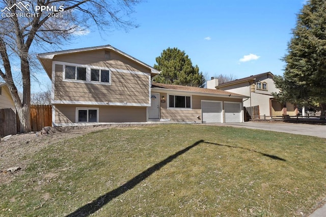 split level home featuring a garage, fence, driveway, a chimney, and a front yard