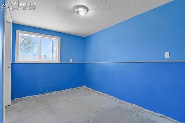 spare room featuring a textured ceiling and concrete floors