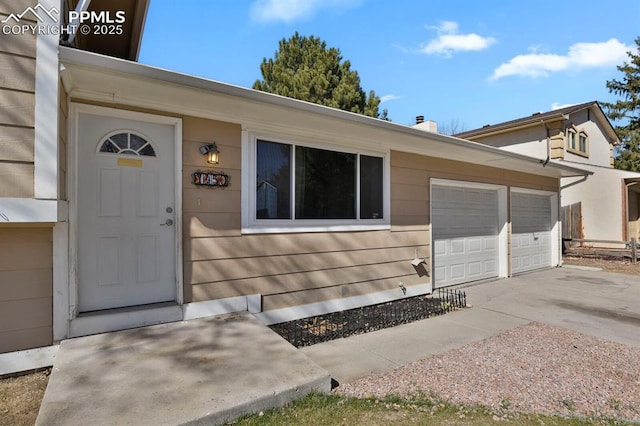 view of exterior entry with a garage and concrete driveway