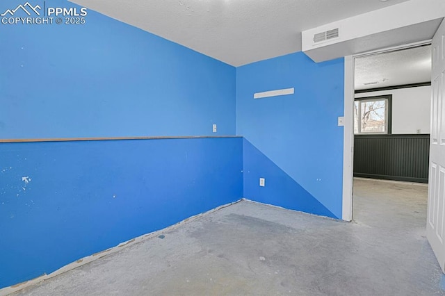 empty room with visible vents, a textured ceiling, and unfinished concrete floors