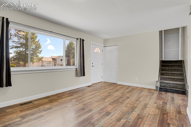 interior space with stairway, baseboards, visible vents, and wood finished floors