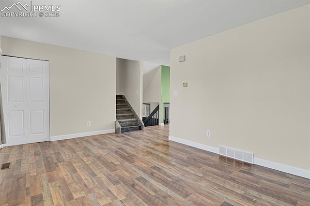 spare room featuring stairs, wood finished floors, visible vents, and baseboards