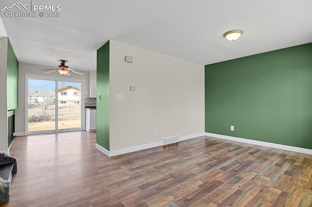 spare room featuring a ceiling fan, wood finished floors, visible vents, and baseboards